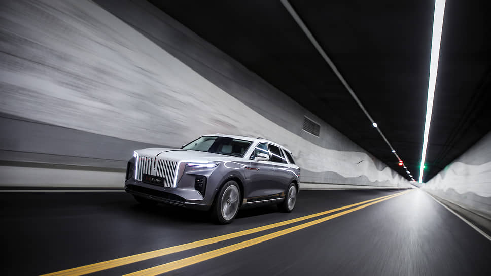 Кроссовер Hongqi E-HS9 щеголяет такой «фишкой», как динамичная светодиодная оптика. Она способна как будто подмигивать вам, улыбаться, и не только. Светящиеся горизонтальные насечки на белых стойках между вторыми дверьми и багажником показывают уровень заряда батареи
