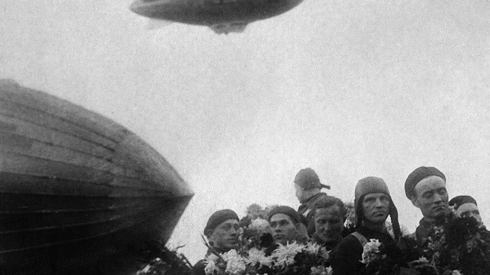 Встреча дирижабля СССР-В6 после рекордного полета. На земле — «СССР-В6», над ним — «СССР-В1». Дирижабль «СССР В-6 Осоавиахим» был построен на базе итальянского дирижабля типа N-4 с различными усовершенствованиями. Для этого в СССР пригласили итальянского конструктора Умберто Нобиле. 29 сентября 1937 года аэростат вылетел из Долгопрудного, где находился проектировочный цех, и приземлился здесь же спустя 130 часов 27 минут, 4 октября 1937 года. При этом был установлен мировой рекорд длительности беспосадочного перелета 