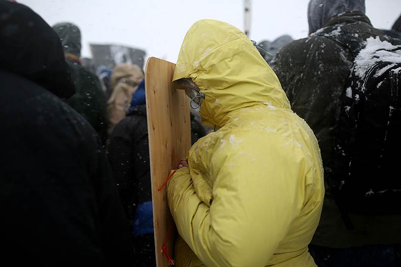 2016 год. Акции против строительства трубопровода в Дакоте. Активист укрывается от ветра листом фанеры  
