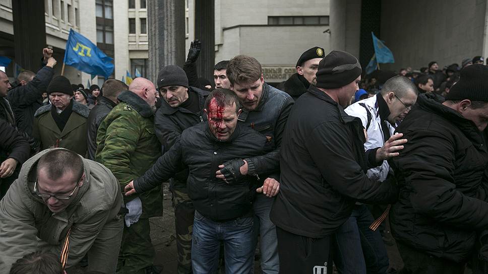Перед входом в парламент жгут плакат, отобранный у пророссийской оппозиции. Люди кидают друг в друга бутылками с водой. Кто-то распылил газ. 
