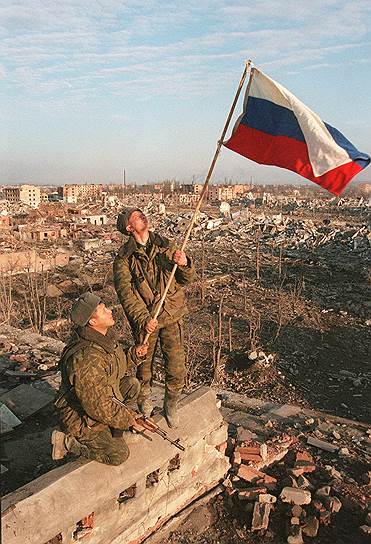 Март 2000 года. Солдаты устанавливают российский флаг над руинами жилого дома в Грозном. Активные бои в городе прекратились в феврале, а боевики переместились в горные районы, где их основные силы были разгромлены в апреле 2000 года