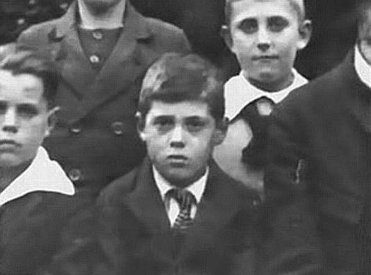 Адольф Эйхман (на фото в 4-м классе гимназии) родился в 1906 году. За маленький рост и темные волосы в Обществе христианской молодежи, где состоял Эйхман, его дразнили «маленьким евреем», что раздражало мальчика. Из-за непростого характера и плохой успеваемости отец забрал его на работу на собственную шахту, где Эйхман проработал около трех месяцев, затем начал изучать электротехнику. В 1932 году он вступил в СС и переехал из Австрии, где запретили деятельность партии, в Германию. Вскоре он поступил на работу в Службу безопасности рейсхфюрера СС Гиммлера, где занимался разбором канцелярии. Во второй половине 1935 года унтерштурмфюрер СС барон Леопольд Иц Эдлер фон Мильденштайн предложил Эйхману перейти в только что организованный им отдел «евреи» в Главном управлении СД. Мильденштайн поручил Адольфу составить справку по книге «Еврейское государство» Теодора Герцля, которая затем использовалась как служебный циркуляр для внутреннего пользования в СС
