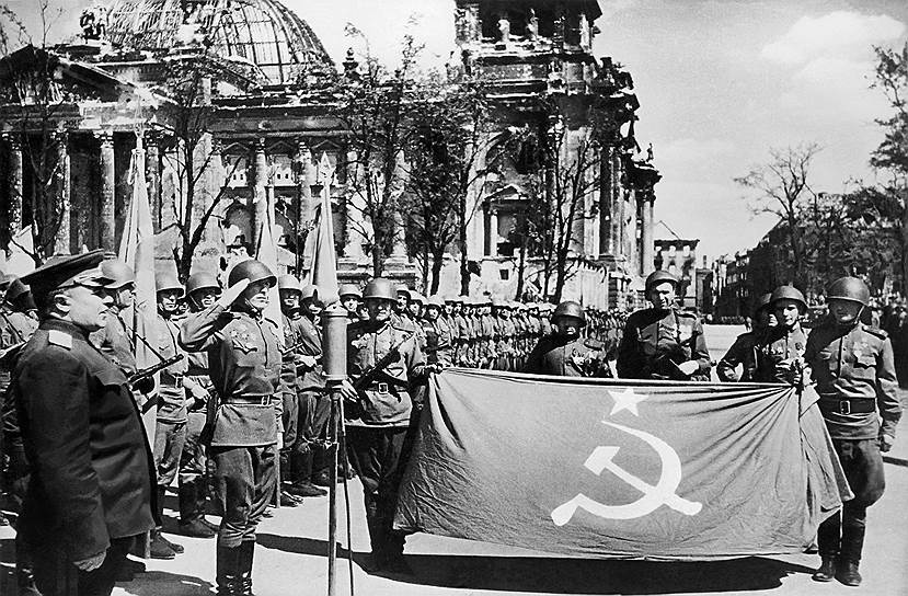 Май 1945. Великая Отечественная война окончена. Государственный флаг СССР отправляется в Москву. Генерал-полковник Берзарин (слева) отдает ему честь на фоне поверженного Рейхстага 