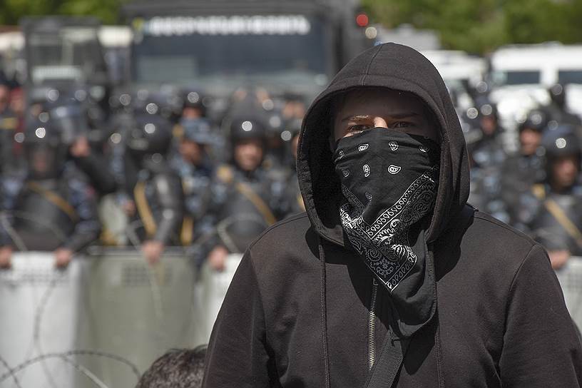 Оппозиоционер на фоне полиции на митинге
