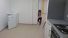 Квартира для большой семьи состоит из проходной кухни, двух небольших спален и санузла. Обстановка скромная: маленький холодильник, электроплита с духовкой и вытяжкой, обеденный стол, мебель из ДСП, металлические кровати с матрасами, пара шкафов