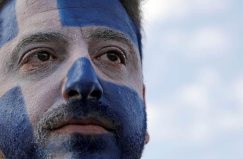 Участник акции протеста раскрасил лицо в цвета греческого флага 