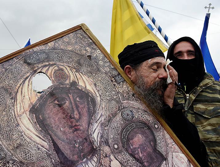 Священник держит икону во время акции протеста  