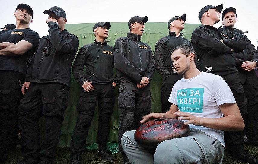 Участник акции протеста на фоне охранников