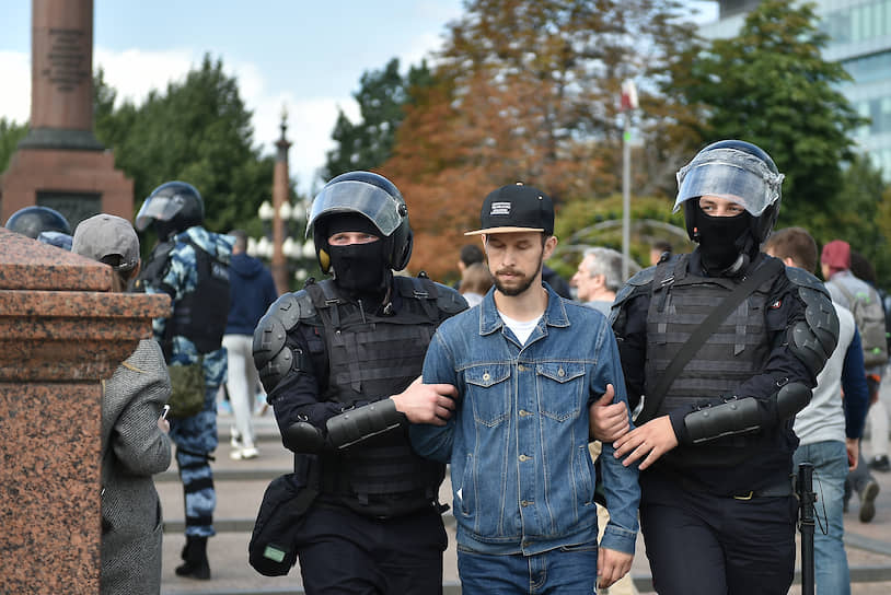 На фото: участник несогласованной акции протеста в сопровождении ОМОНа