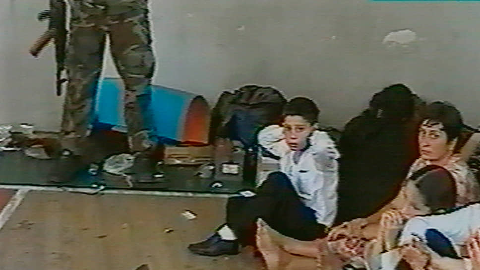 Заложники в спортивном зале бесланской школы. Рядом с ними один из захватчиков 