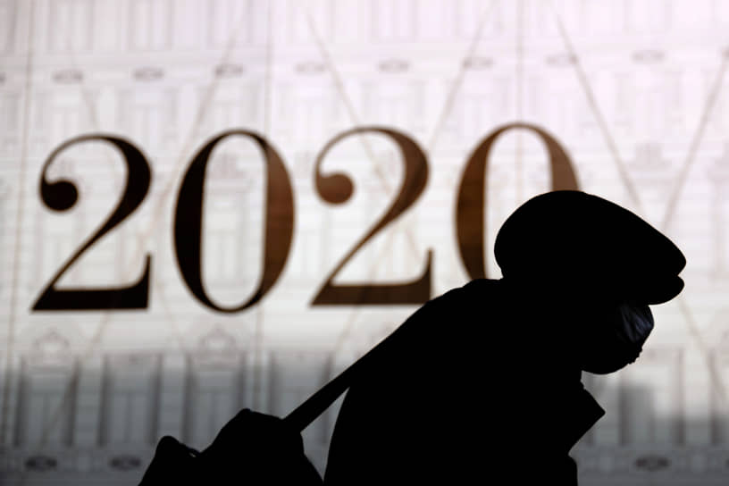 Мужчина в медицинской маске в Москве на фоне плаката с надписью «2020»