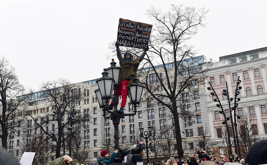 Мужчина с плакатом против Алексея Навального на фонарном столбе