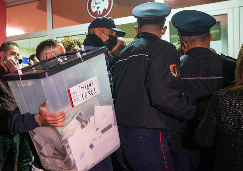 Член избирательной комиссии несет урну с голосами для подсчета после завершения выборов в Албании 