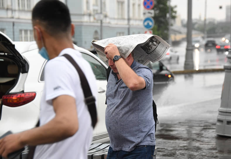 Мужчина укрывается газетой в центре города