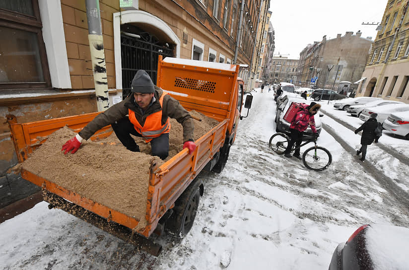 Сотрудники коммунальной городской службы посыпают песком обледенелый тротуар