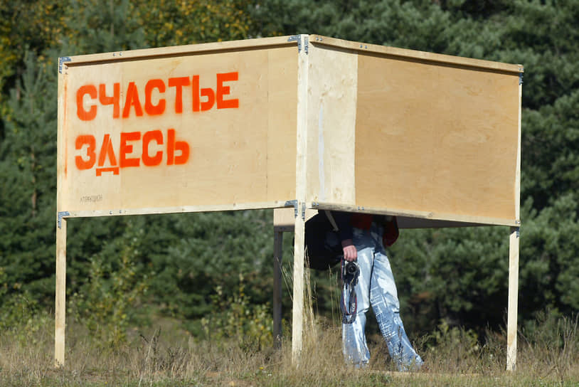 Фотограф фестиваля современного искусства в Клязьме стоит за щитом с надписью «Счастье здесь» 