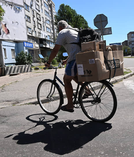 Мужчина на велосипеде с коробками на багажнике едет по улице Бердянска 