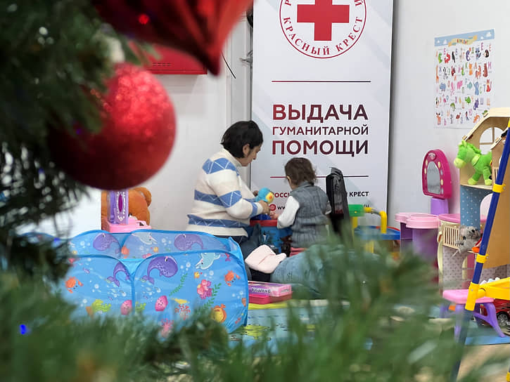 Мама с ребенком ожидает своей очереди на получение набора с гуманитарной помощью и ваучеров в магазин одежды в отделении Российского Красного Креста 