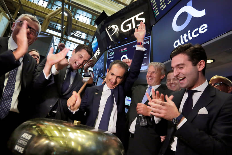 Основатель Altice Патрик Драи (в центре) звонит в церемониальный колокол, когда его компания выходит на IPO. Нью-Йоркская фондовая биржа, 22 июня 2017 года 
