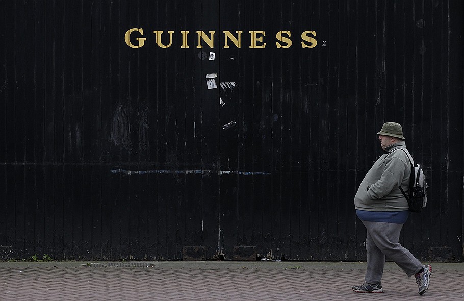 Мужчина, проходящий мимо пивного завода Guinness в центре Дублина (Ирландия)