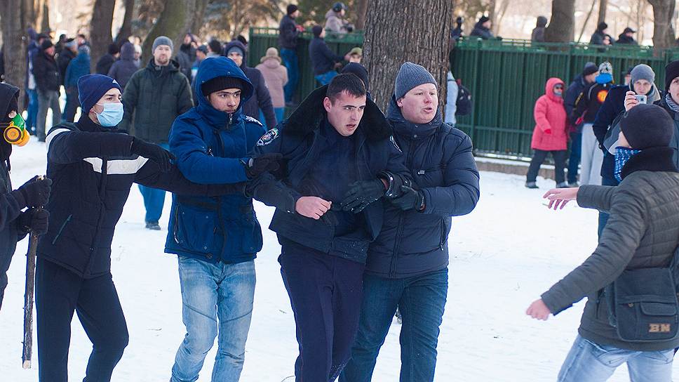Митингующие ведут милиционера возле здания Днепропетровской областной государственной администрации для оказания медицинской помощи 