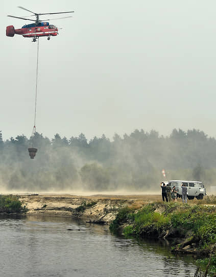 Вертолет МЧС во время забора воды из реки