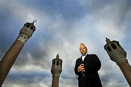 Имам Абдул Хиссаин на фоне мечети Восточного Лондона в историческом районе Уайтчепел