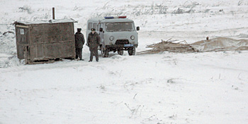 Милиционеры, охраняющие дорогу к оврагу, поставили себе бытовку с печкой - они здесь всерьез и надолго
