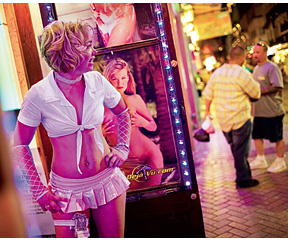 В пятницу вечером сотрудница «Джентльменского клуба» стоит на Бурбон-стрит и завлекает посетителей в заведение