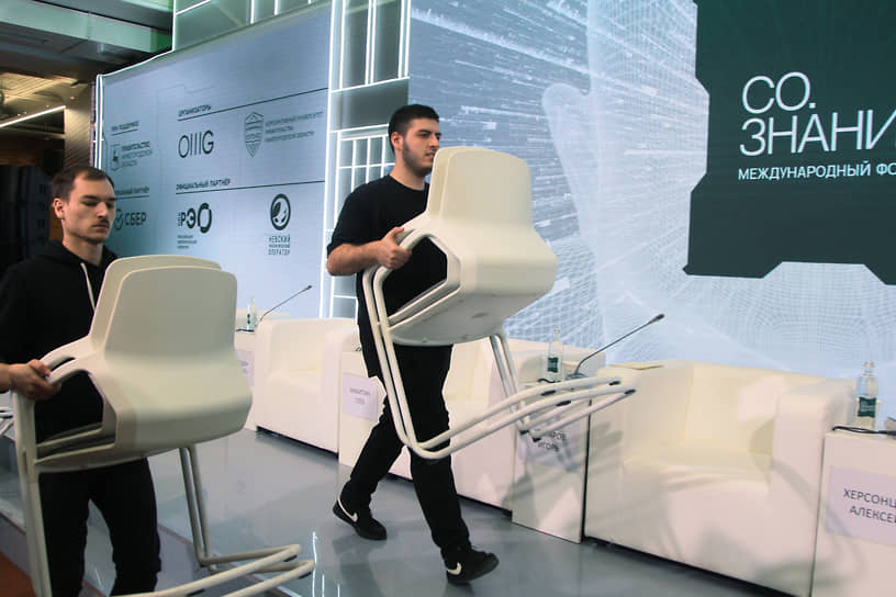 Рабочие вносят стулья для участников форума 
