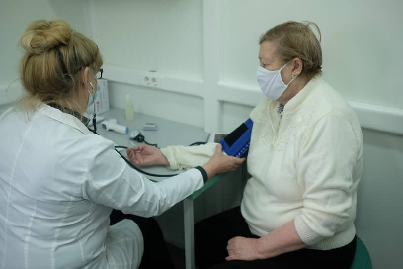 Вакцинация от коронавирусной инфекции COVID-19 вакциной Гам-КОВИД-Вак ("Спутник V"). Жанровая фотография. Медицинский работник в мобильном пункте вакцинации во время вакцинации пациента