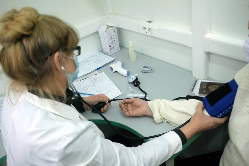 Вакцинация от коронавирусной инфекции COVID-19 вакциной Гам-КОВИД-Вак ("Спутник V"). Жанровая фотография. Медицинский сотрудник измеряет давление у пациента в мобильном пункте перед вакцинацией
