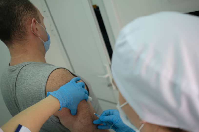 Вакцинация от коронавирусной инфекции COVID-19 вакциной Гам-КОВИД-Вак ("Спутник V"). Жанровая фотография. Медицинский работник в мобильном пункте вакцинации во время вакцинации пациента