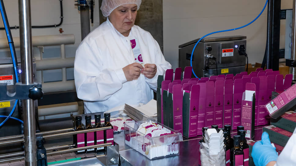 Работница на линии по розливу в бутылки и упаковке амарантового масла