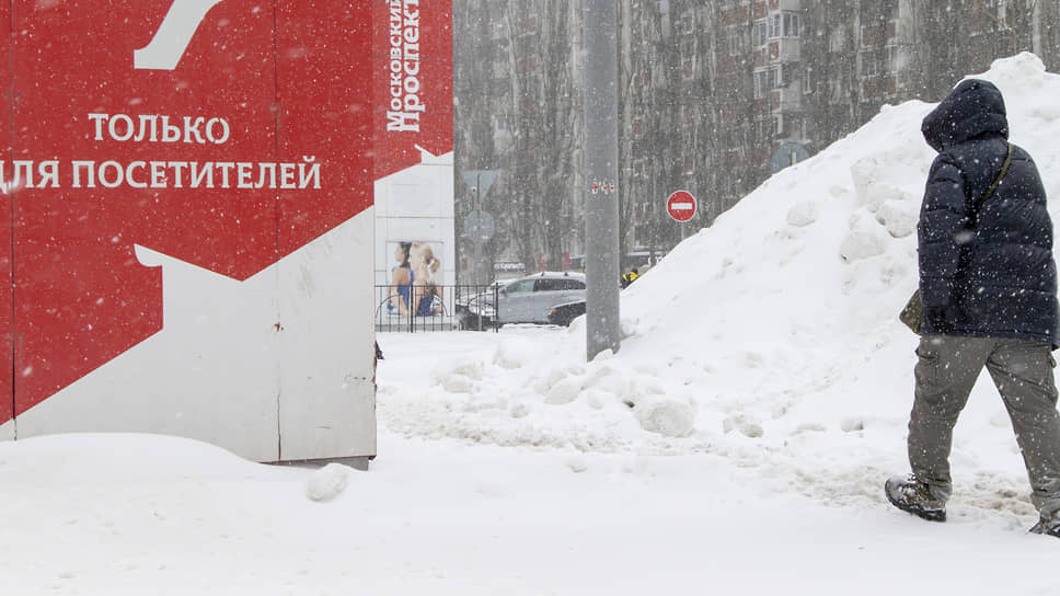 Житель города проходит мимо высоких сугробов на улице Воронежа 