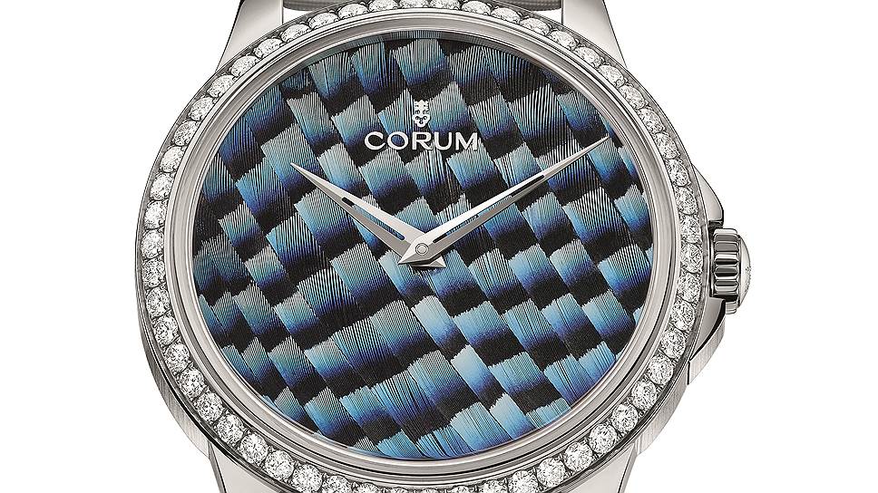 Модели Corum (слева направо) — с розовым корпусом и перьями павлина, со стальным корпусом и перьями голубой сойки и с розовым корпусом и перьями павлина. На ободке — 126 бриллиантов; внутри — автоматический калибр Corum CO110