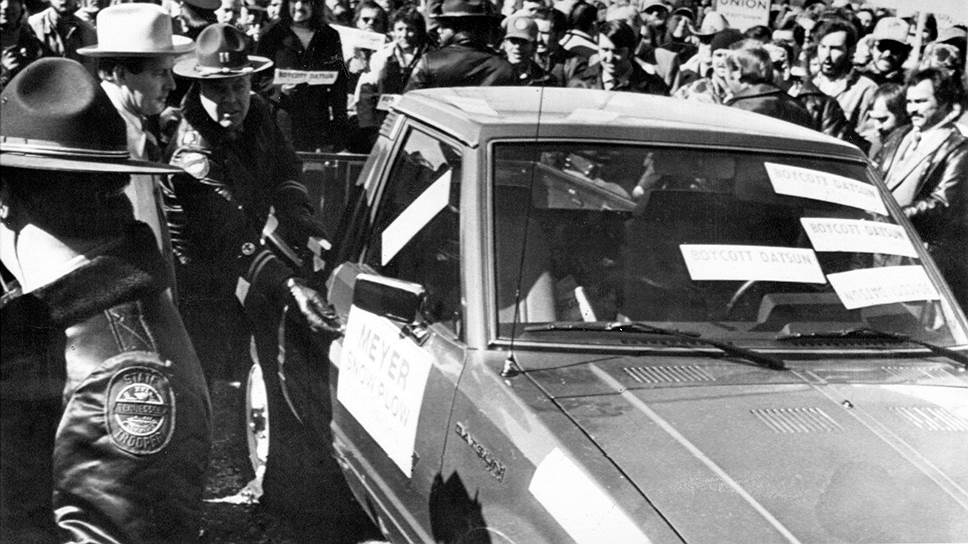 В 1980-е годы профсоюзы и промышленники выражали недовольство засильем японского импорта ударными методами (на фото — губернатор Теннесси Ламар Александер, объявивший о контракте с компанией Nissan на строительство завода, пробивается к своей машине марки Datsun под прикрытием полицейских, 1981 год) 