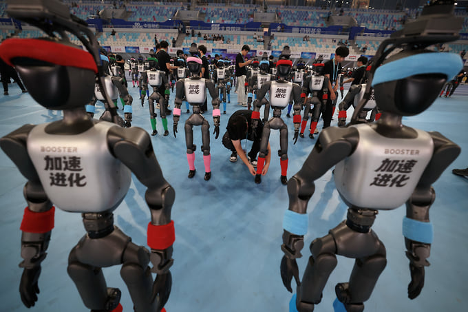 Инженер настраивает робота Booster Robotics перед открытием Игр