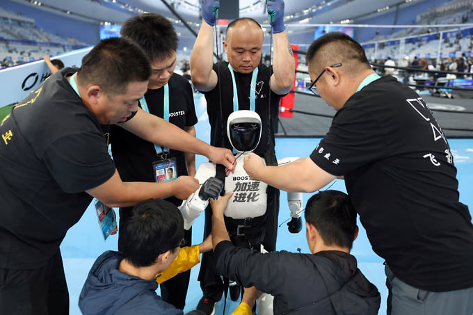 Сотрудники готовят робота Booster Robotics к открытию Игр