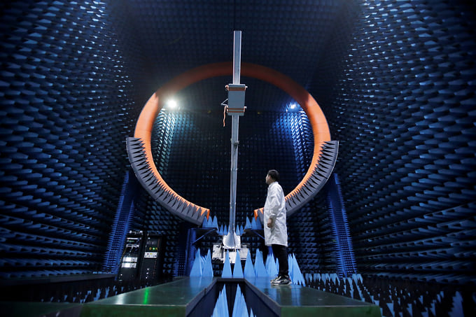 Инженер под антенной базовой станции 5G внутри системы тестирования на производственном комплексе Huawei (провинция Гуандун, Китай, 2019 год)