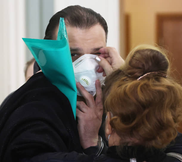 Мать арестованного Александра Куфлина надевает ему респиратор