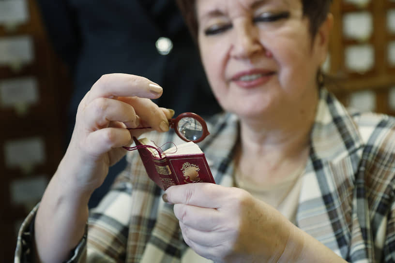 Заместитель директора библиотеки ННГУ Елена Баскакова читает микрокнигу с лупой