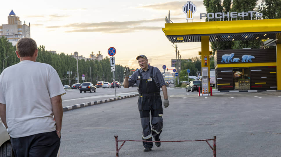 Сотрудник АЗС «Роснефть» показывает автомобилистам, что на станции доступен бензин АИ-92