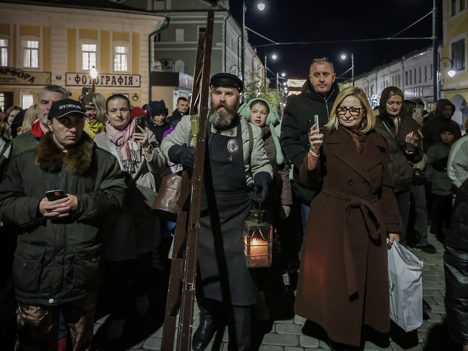 Он идет по улицам, рассказывая об истории уличного освещения в России и Рыбинске, а также о старинной профессии