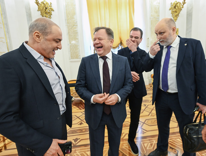 Хормейстер Михаил Турецкий (слева), саксофонист Игорь Бутман (второй слева) и председатель комиссии Общественной палаты по вопросам суверенитета, патриотическим проектам и поддержке ветеранов Владимир Рогов (справа) перед встречей Владимира Путина с доверенными лицами в Андреевском зале Большого Кремлевского дворца, 2024 год